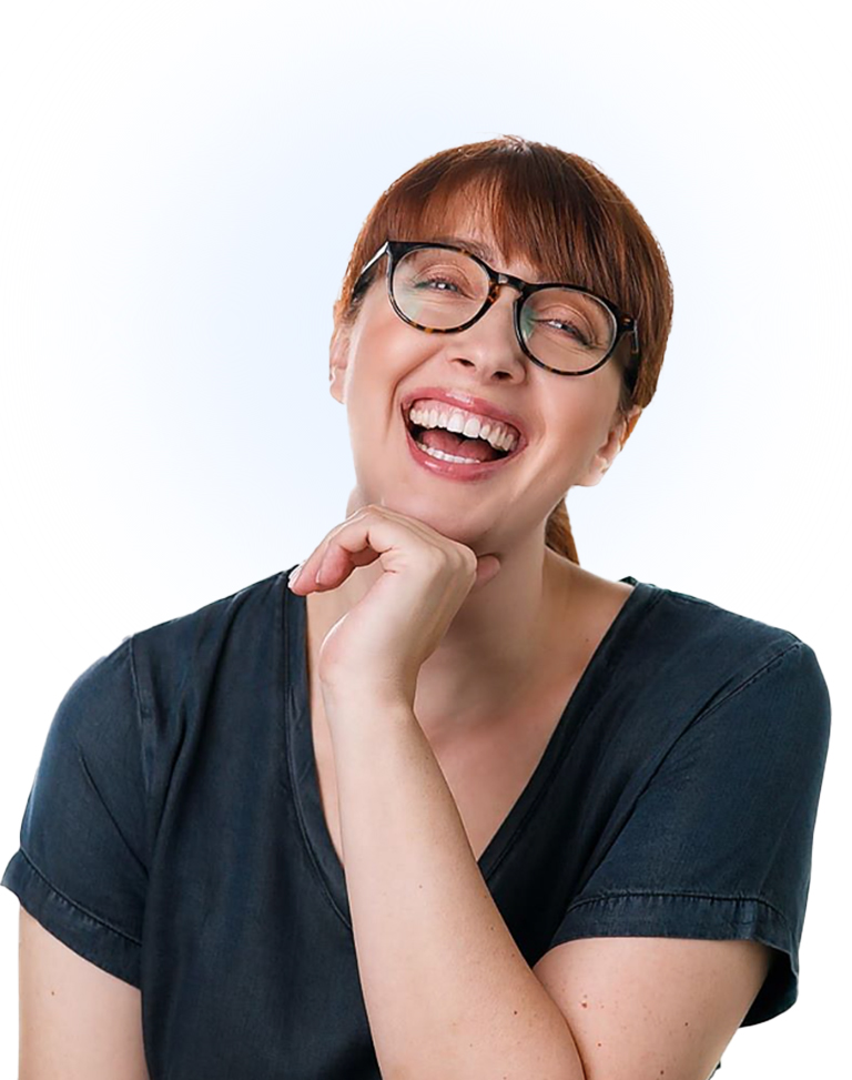 Woman with short red hair and black glasses laughing, head tilted slightly, wearing a dark T-shirt against a light background.